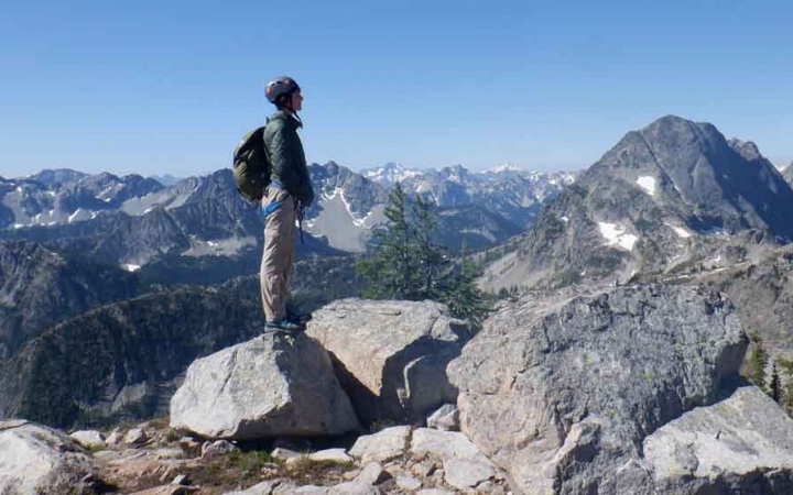 a person stands on a rock overlooking a vast mountainous landscape on an outward bound gap year expedition 